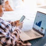 woman using her phone and laptop to check rates