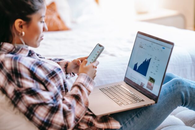 woman using her phone and laptop to check rates