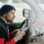 man in the driver's seat holding a smartphone