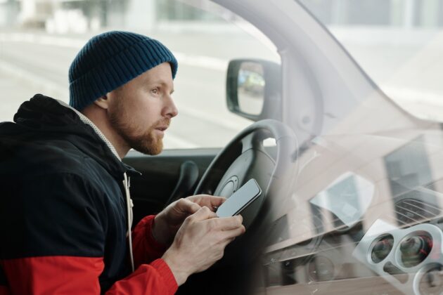 man in the driver's seat holding a smartphone