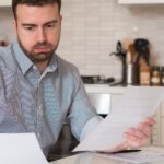 A man calculating bills, debts and repayments to improve his bad credit score